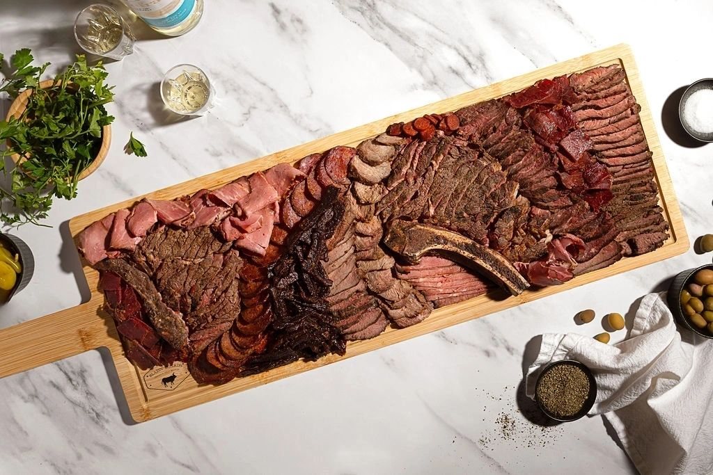 Our long board on marble: pastrami, brisket, salami and a bone-in rib, with olives and parsley