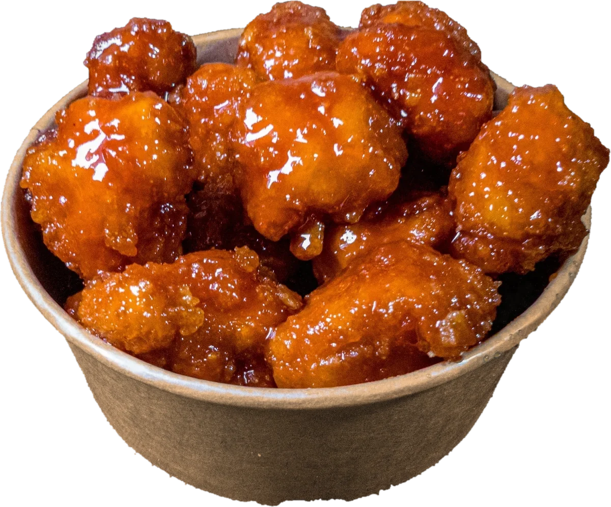 A kraft bowl of Original Hot Poppers, chicken bites in a glossy sweet and spicy glaze