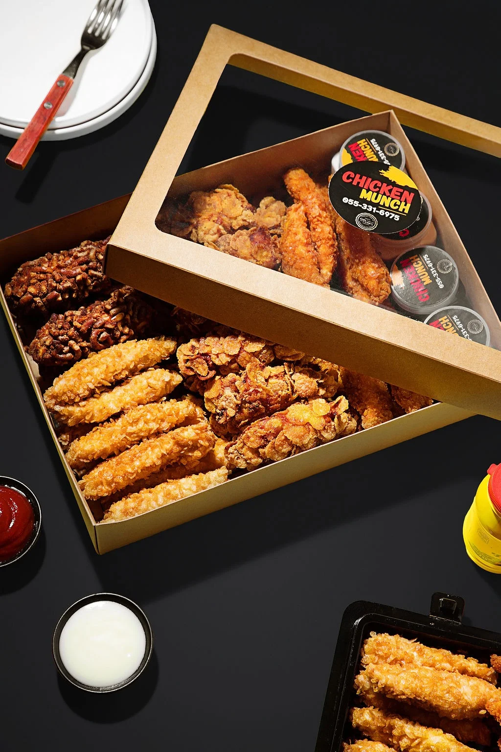 A Chicken Munch box from above, with chicken fingers, sauce pots and a tray of tenders beside it