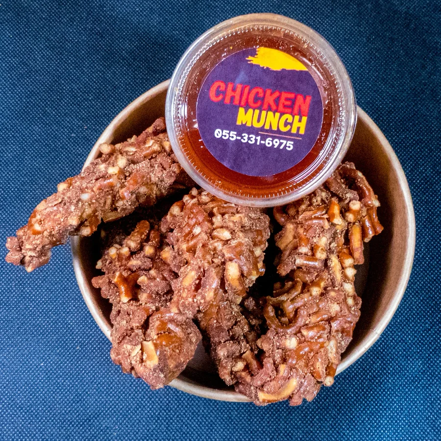 Pretzel chicken fingers in a kraft bowl, from above, with a Chicken Munch sauce pot