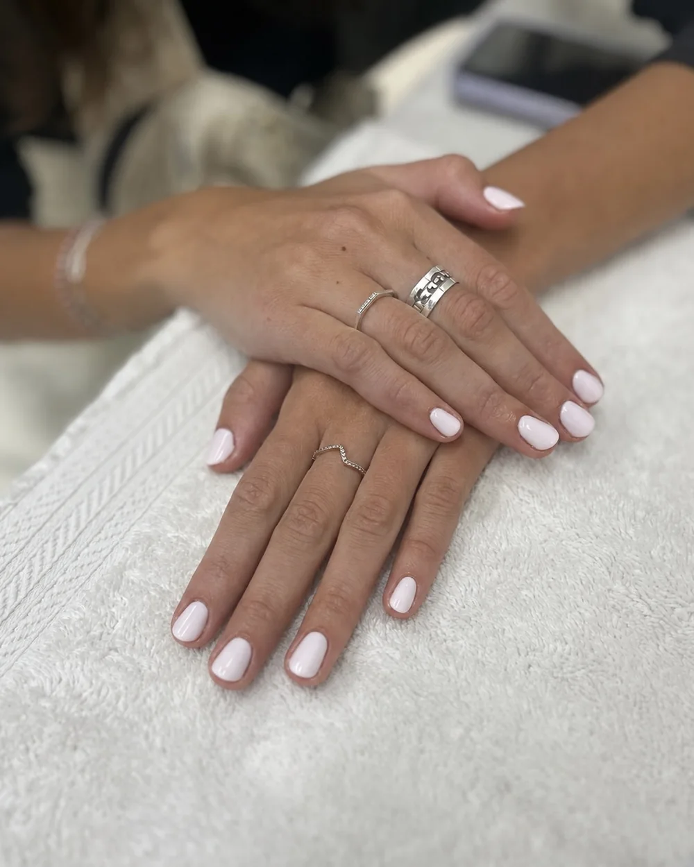 White gel nails on a client, hands on a towel