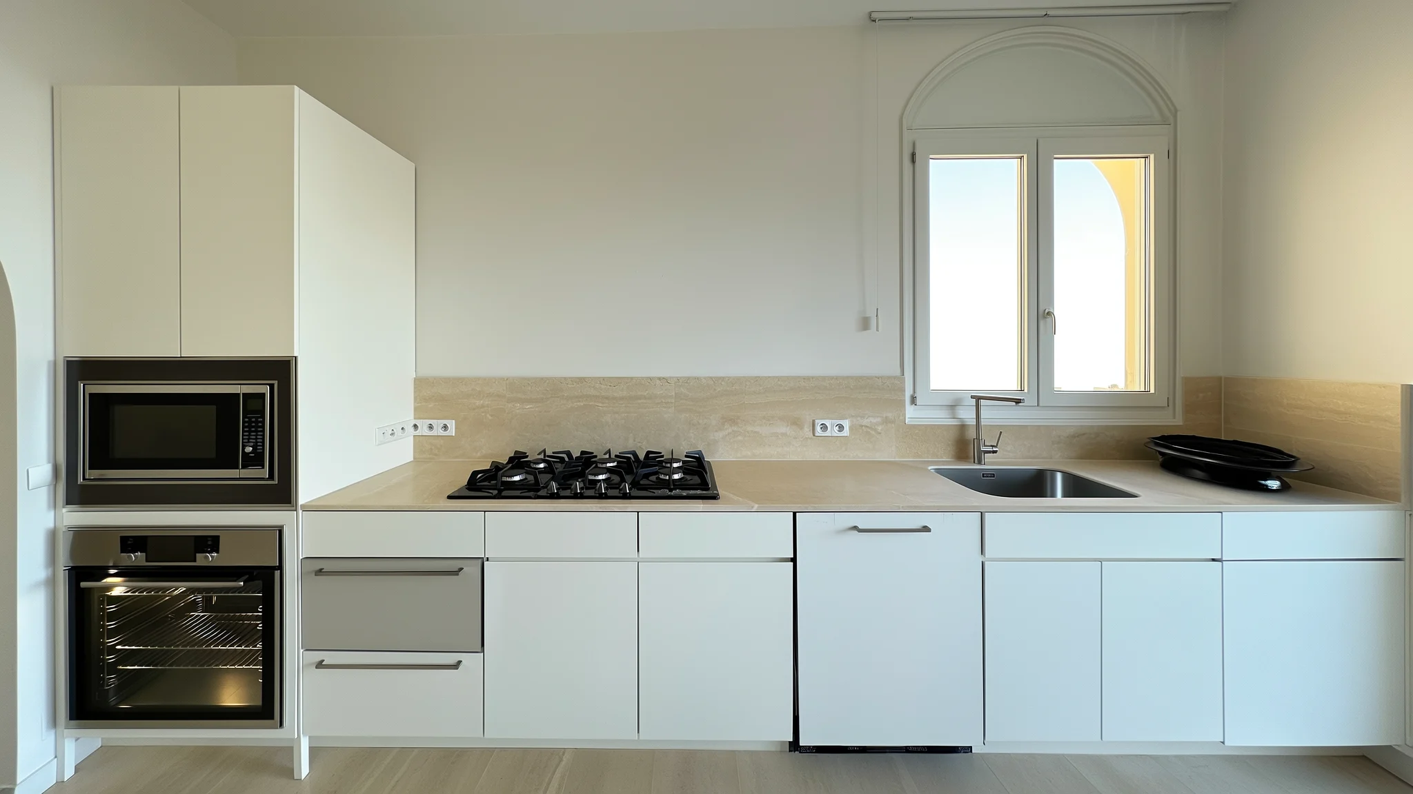 A rental kitchen: oven, microwave, gas stovetop, countertops, sink and a hot plate along one wall