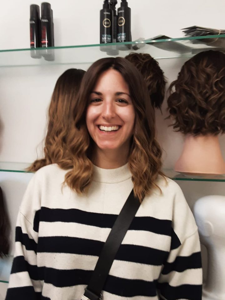 A client in a striped sweater with a soft shoulder-length brown wig
