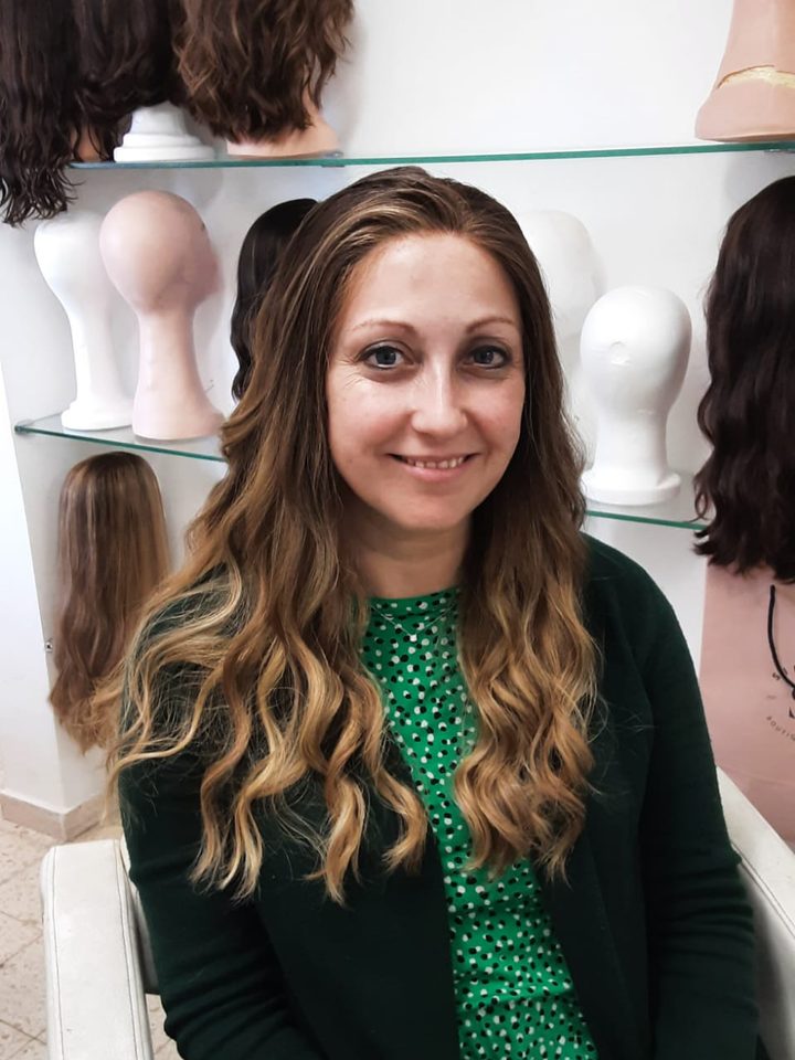 A client in a long wavy light-brown wig with a green cardigan