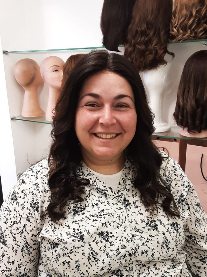 A client laughing in a dark curled wig