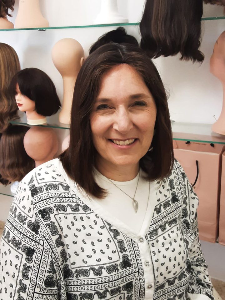 A client smiling in a shoulder-length dark wig