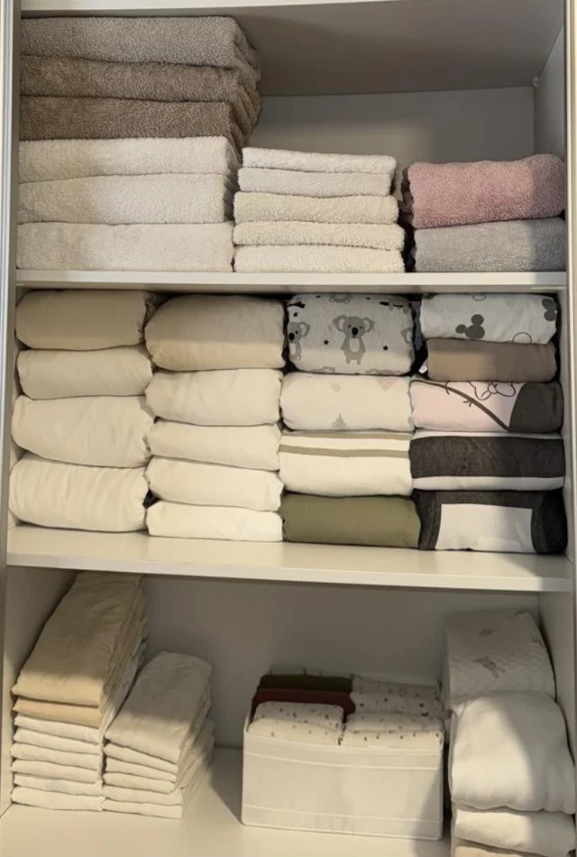The same cupboard with towels and sheets folded in neat stacks