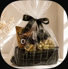 A black and gold cosmetic bag filled with treats, wrapped in cellophane