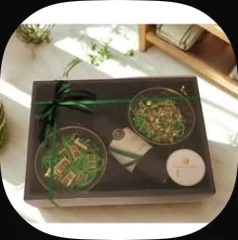 Two small gold-rimmed glass bowls in a black box tied with a green ribbon