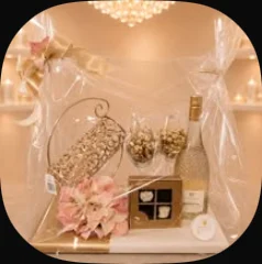 Gold wine holder with wine glasses, a bottle and flowers, wrapped in cellophane