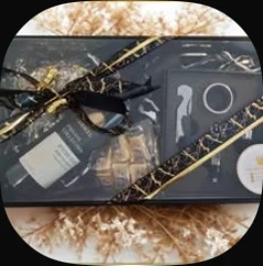 A bottle opener set and a bottle in a black box with a gold ribbon