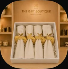Four white napkins with gold apple rings in a box