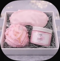 A pink silk eye mask, bath flower and body scrub in a box