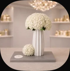 A white ribbed vase of white roses on a grey board