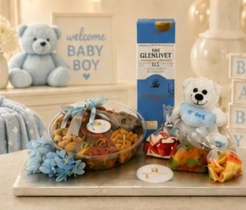 A welcome baby boy gift: a teddy bear, sweets in a ribboned tray and a bottle