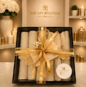 Rolled linens in a black box, tied with a wide gold ribbon