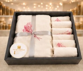 A white towel set with pink embroidery in a black box