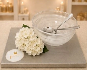 A glass bowl and spoon on a silver board with white hydrangeas